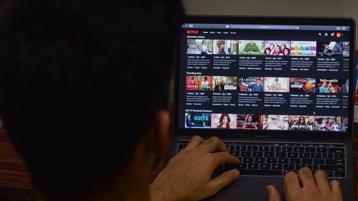 Un hombre navega por el menú de Netflix en su portátil.