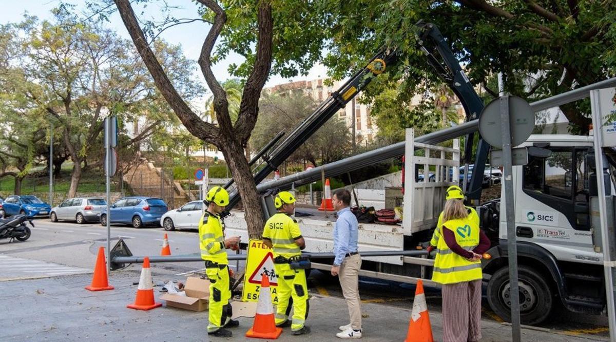 Operarios municipales cambian una de las farolas de la calle.