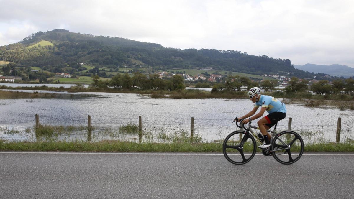 Un ciclista circula por la carretera que bordea la ría de Villaviciosa.