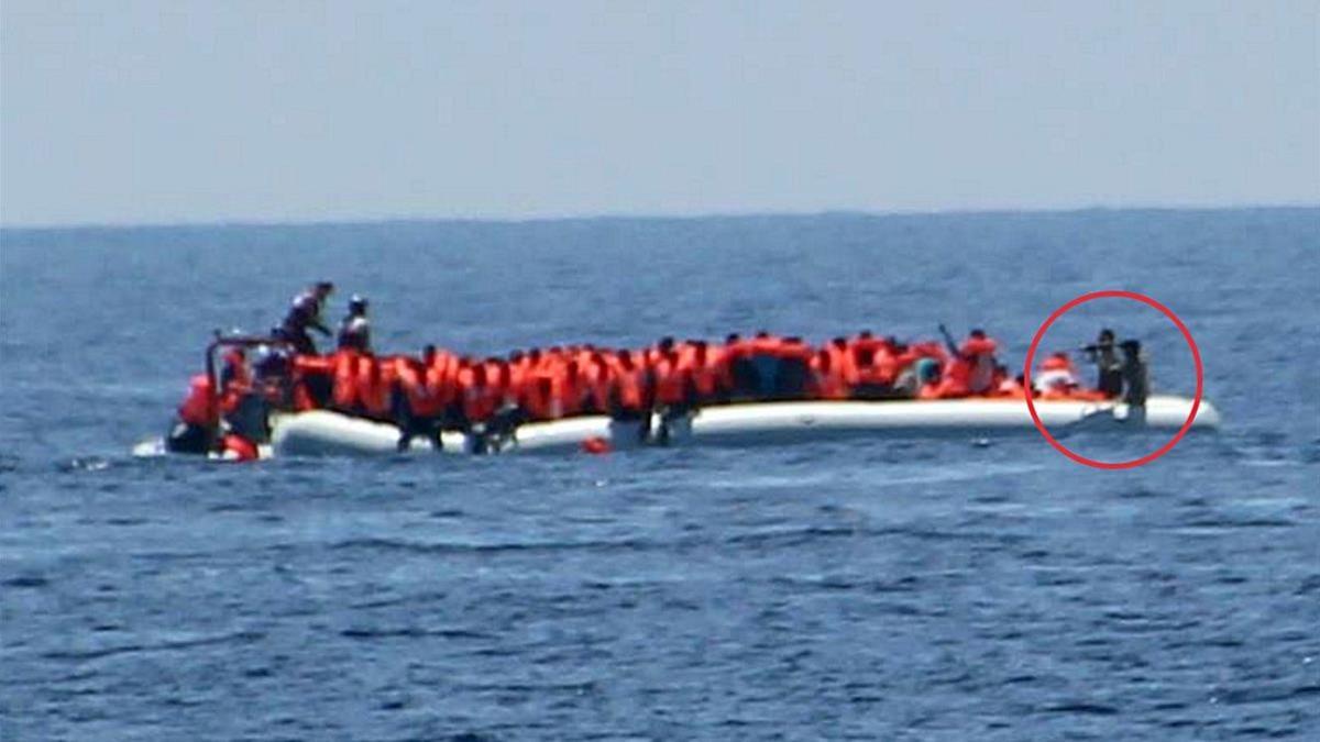 Unos guardacostas libios apuntan con sus armas a un grupo de inmigrantes y refugiados que navegan en una barca por el Mediterráneo, el 24 de mayo.