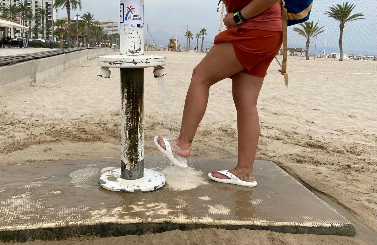 Una mujer se quita la arena en un lavapiés de la playa de San Juan, este miércoles.