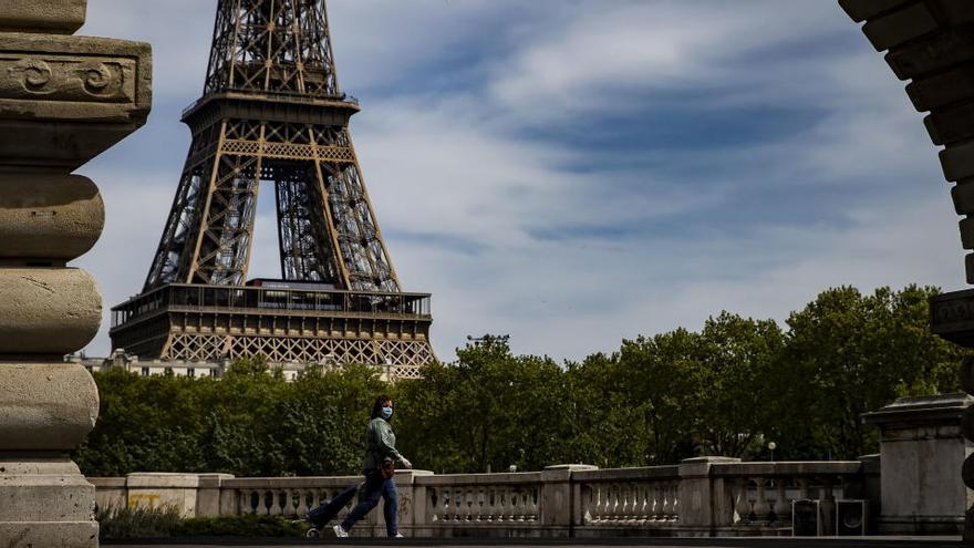 Una mujer pasea frente a la Torre Eiffel.