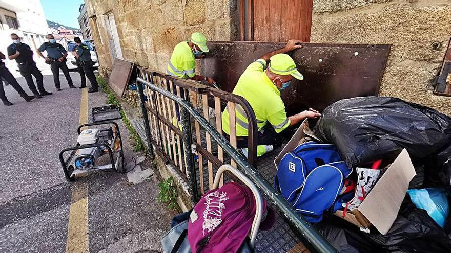 Operarios municipales tapiando la vivienda, con los enseres a la puerta.   | // SANTOS ÁLVAREZ