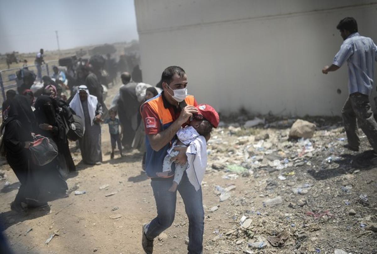 Un enfermero atiende a un bebé sirio que acaba de pasar a territorio turco.