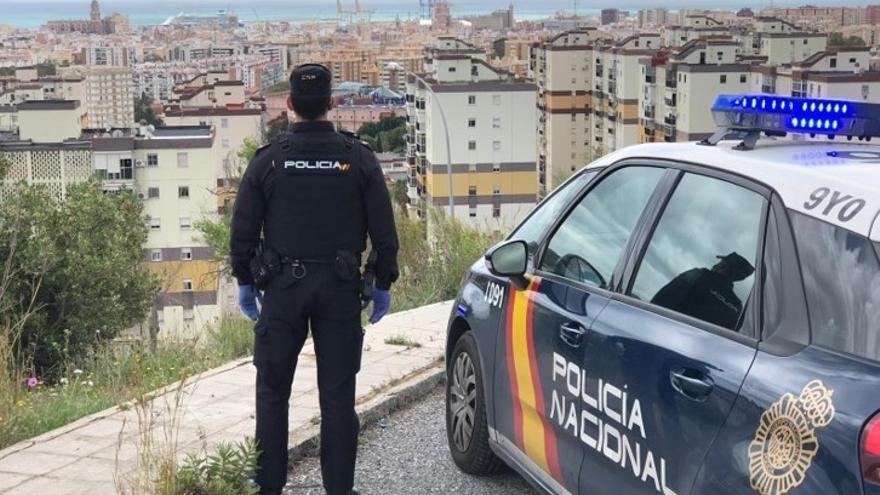 Archivo - Agente de la Policía Nacional de Málaga junto a un vehículo