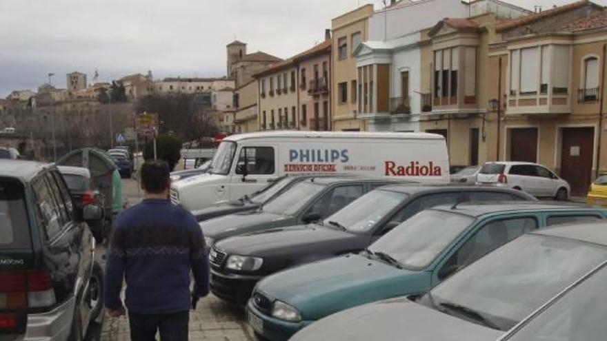 Un hombre camina entre coches en el barrio de La Horta.