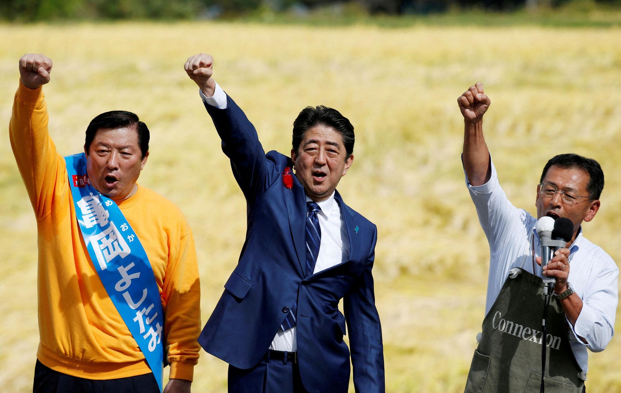 FILE PHOTO: Japan's Prime Minister Shinzo Abe, who is also ruling Liberal Democratic Party leader, shout slogans with a local candidate and a supporter during an election campaign rally in Fukushima