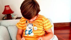 Un niño, en su casa, viendo el móvil.
