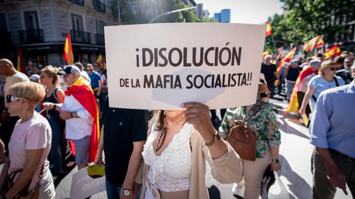 Manifestante porta pancarta con lema '¡Disolución de la mafia socialista' durante  una manifestación para exigir la dimisión del presidente del Gobierno, Pedro Sánchez, a 23 de mayo de 2026, en Madrid (España). La movilización ha sido convocada por Sociedad Civil Española bajo el lema ‘¡Sánchez, dimisión ya!’.