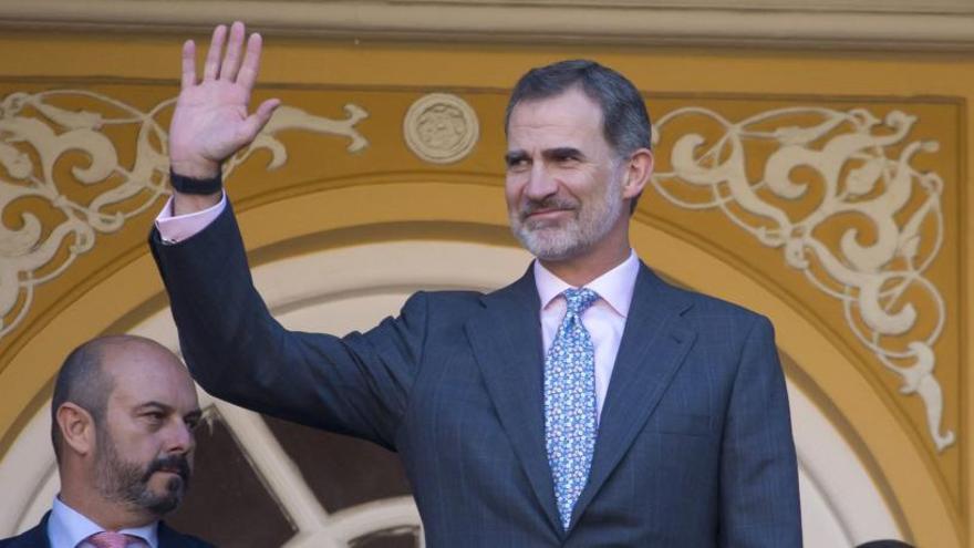 El Rey Felipe VI saluda con su mano derecha.