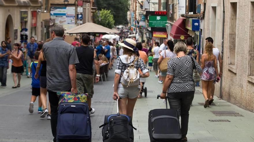 Turistas cargados con maletas en la calle Oms de Palma.