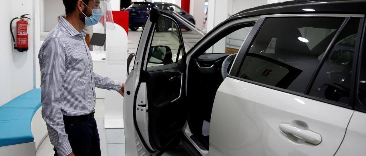 Un trabajador de un concesionario enseña un coche.