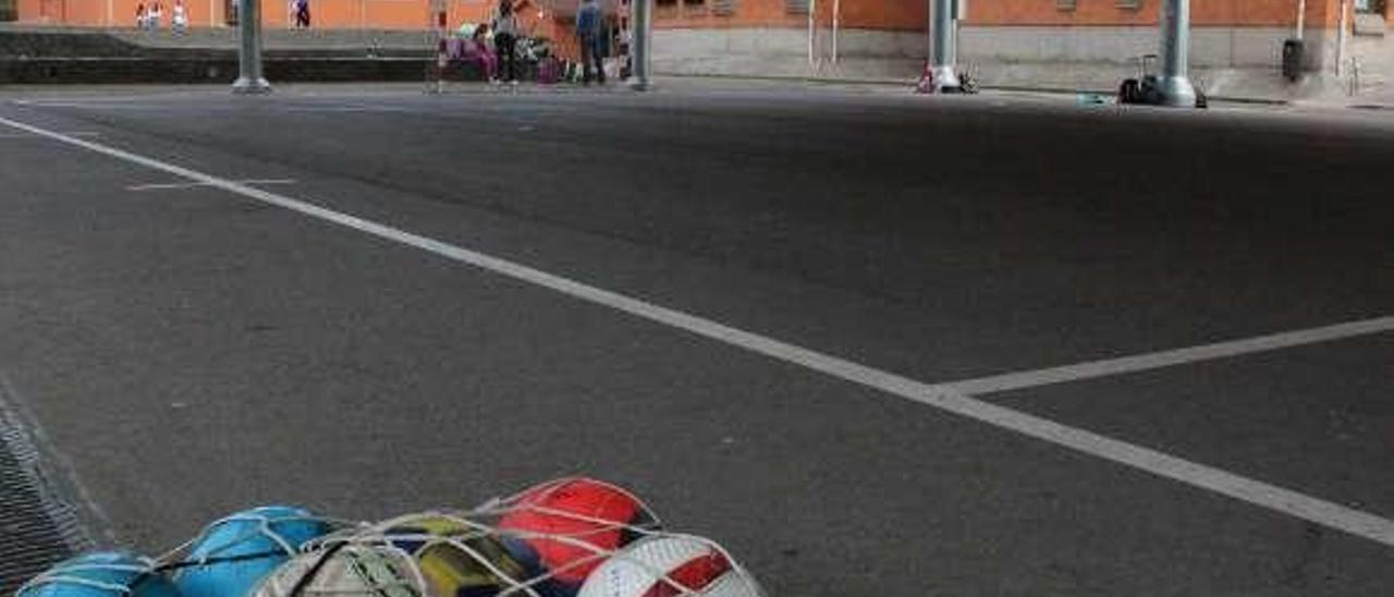 Balones en la pista exterior. Al fondo, el polideportivo.