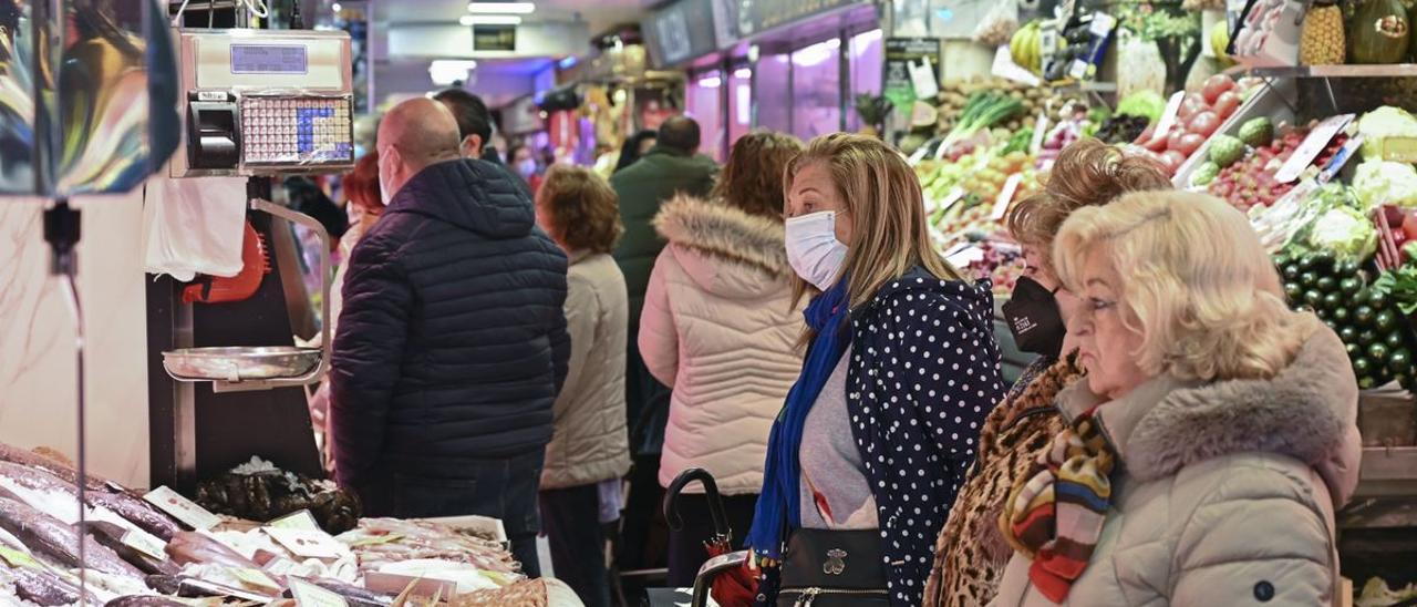 Varias clientas con y sin mascarilla aguardan a ser atendidas en un puesto de un mercado de Madrid.