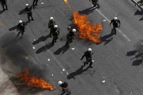 Greek riot police avoid flames from two molotov cocktails at a protest march by Greece's Communist party in central Anthens during a 24-hour labour strike