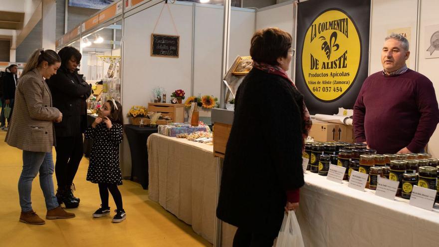 Varios asistentes visitan los puestos de la feria. |