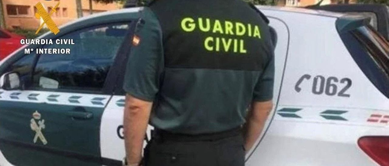 Archivo - Un agente de la Guardia Civil junto a su vehículo.