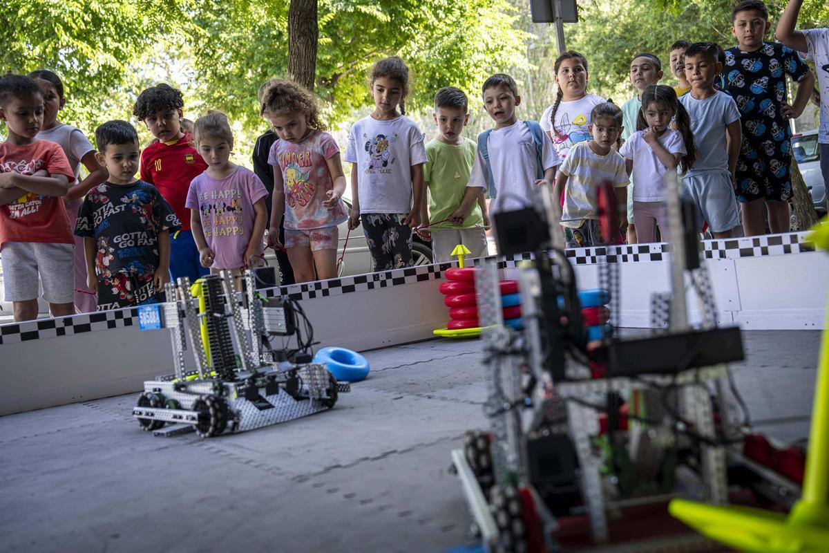 Un grupo de niños y niñas observa los robots en la jornada de exhibición en La Mina, en Sant Adrià de Besòs.