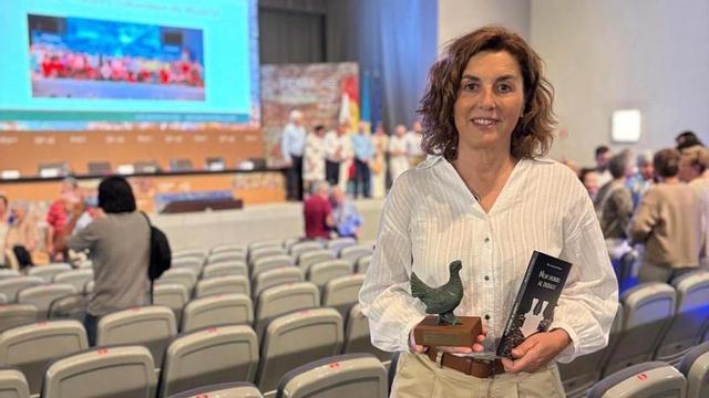 María José Hevia Velasco posa, en el salón de actos de la FIDMA, con su nueva novela en una mano y el Urogallo del Centro Asturiano de Madrid en la otra; a la izquierda, la portada de «Un horru al debalu» y, al otro lado, con su hermano José Ángel Hevia, durante la presentación del libro. |