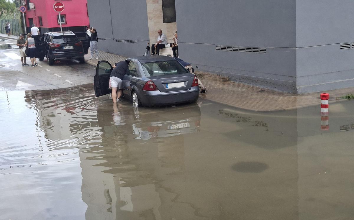 Los vecinos empujan un coche atrapado en la hondonada urbana del Grupo San Andrés