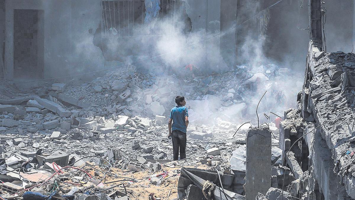 Un joven observa la destrucción de un edificio en Gaza, este martes, en un nuevo ataque israelí.