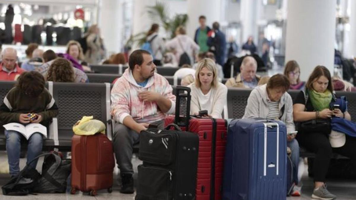 Unos ciudadanos esperan en la puerta de embarque.