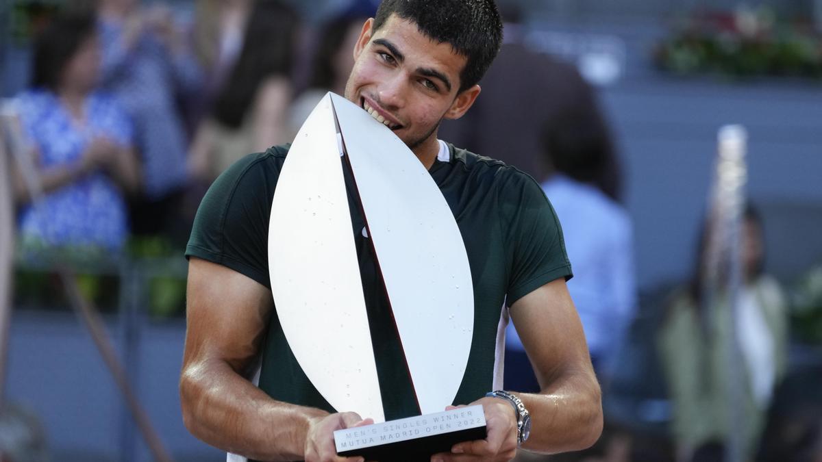 Carlos Alcaraz beißt nach seinem Sieg in den Pokal.