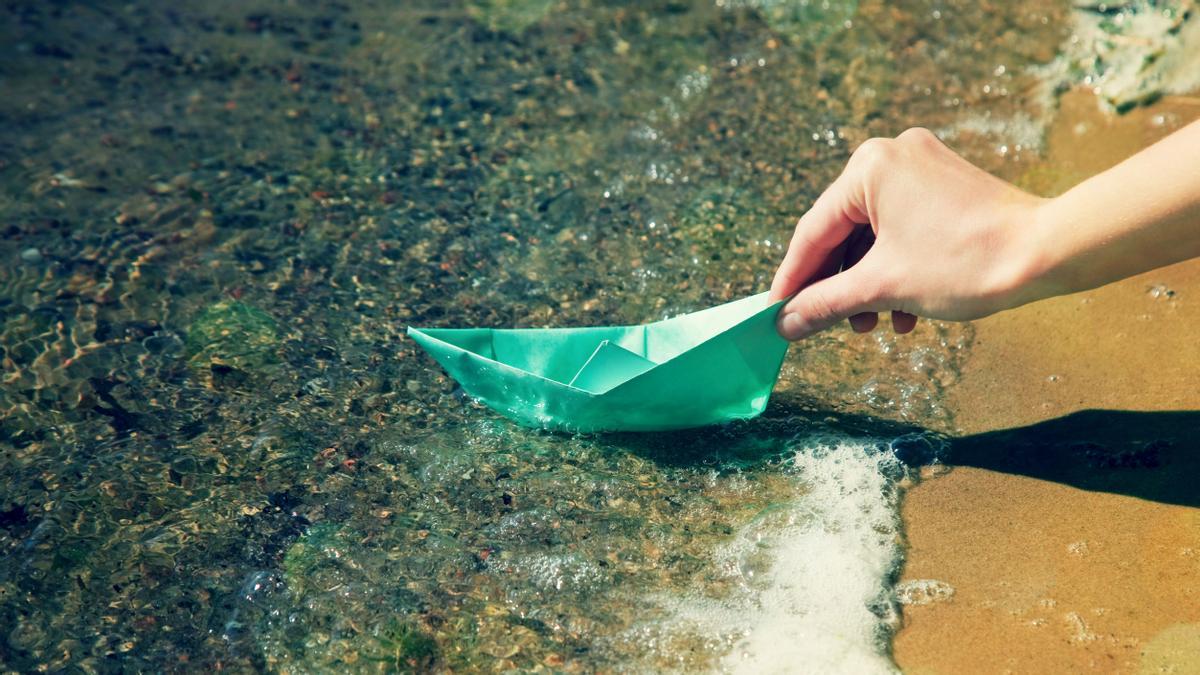 BARCO DE PAPEL hand with paper boat near water