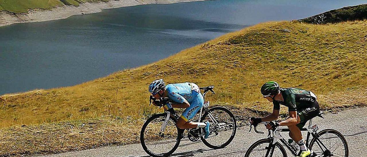 A la izquierda, Jakob Fuglsan, sentado sobre el cuadro de la bicicleta en un descenso en el Tour de Francia