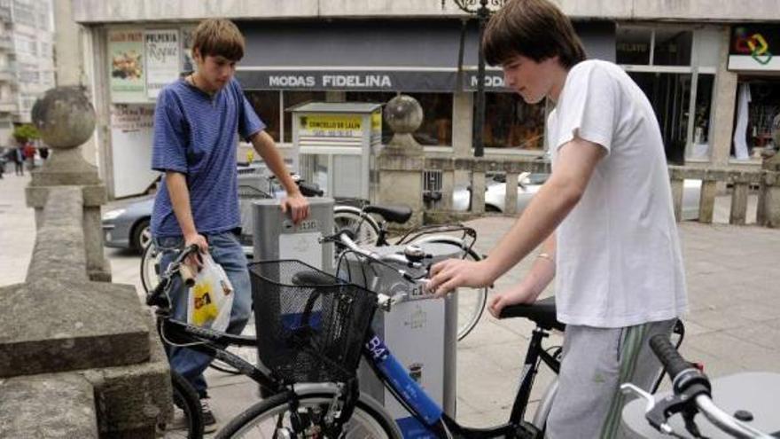 Dos jóvenes prueban las bicicletas, operativas desde 2010, en el puesto de Praza da Torre.  // Bernabé/J.Lalín