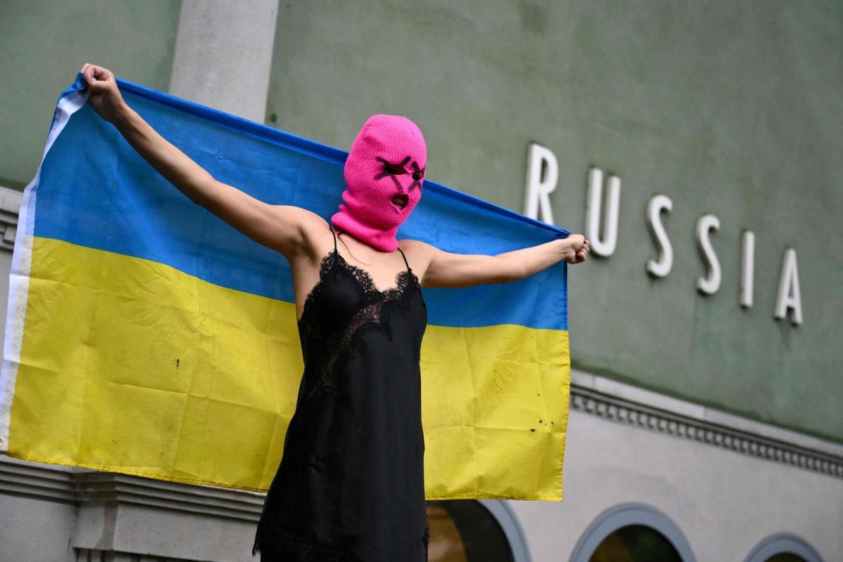 Un miembro de las activistas Pussy Riot con la bandera ucraniana delante del pabellon ruso de la Biennal de Venecia.