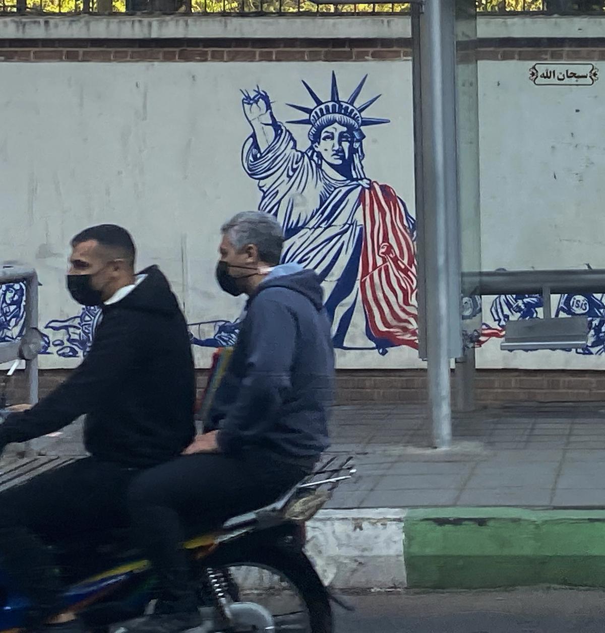 Dos hombres pasan en moto  delante de lo que fue la Embajada de EE UU en Teherán.