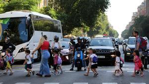 Una escuela de infantil cruza la cale de Aragó, con motos, coches, autocares y taxis esperando para pasar