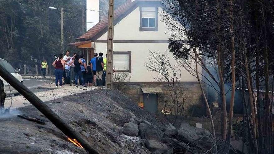 Vecinos de As Neves ante una casa que se salvó de las llamas.