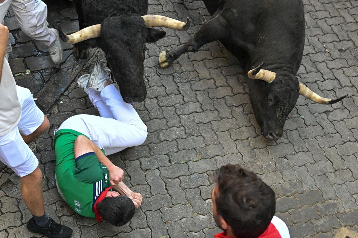 PAMPLONA, 13/07/2025.- Uno de los mozos cae al paso de los toros de la ganadería gaditana de La Palmosilla s durante el séptimo encierro de los Sanfermines 2025 este domingo en Pamplona. EFE/Daniel Fernández