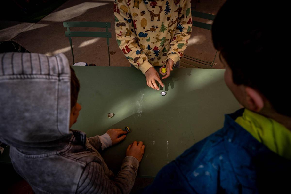 Niños jugando a las chapas en el patio de la escuela.