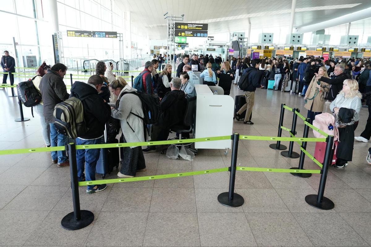 Varios pasajeros buscan sus tarjetas de embarque para mostrar en el control de seguridad de la terminal T1.