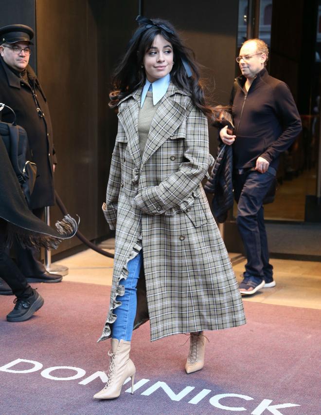 Camila Cabello con un trench oversized de cuadros y un lazo oscuro a modo de diadema en el pelo paseando por las calles de Nueva York