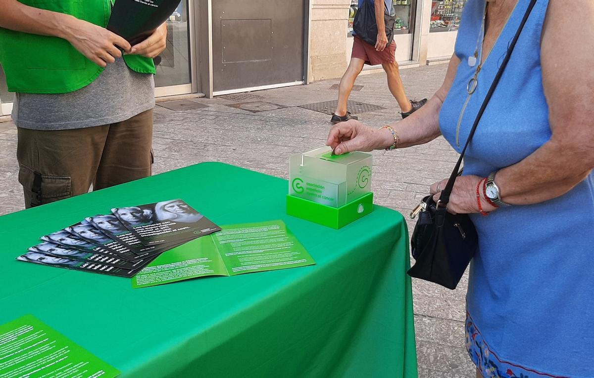 Una mujer hace un donativo a la AECC en la Plaza Félix Sáenz de Málaga