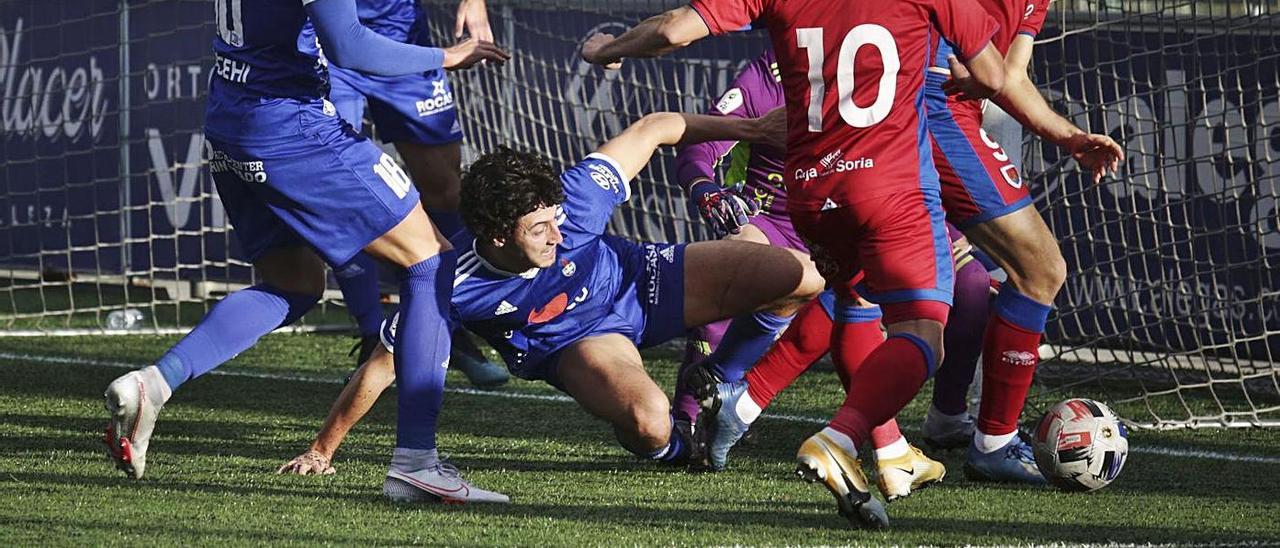 Aitor Elena trata de quitarle el balón al delantero del Numancia Asier Benito, con Menudo de espaldas