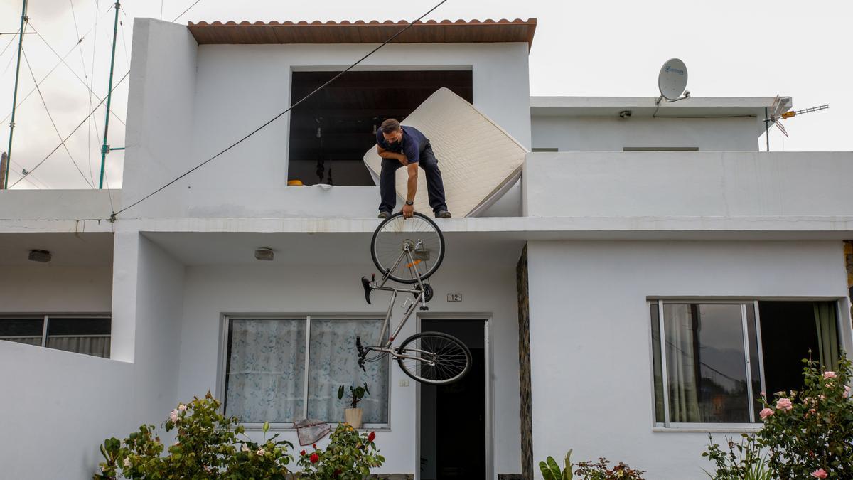 Un hombre saca una bicileta por el balcón de su casa en Todoque.