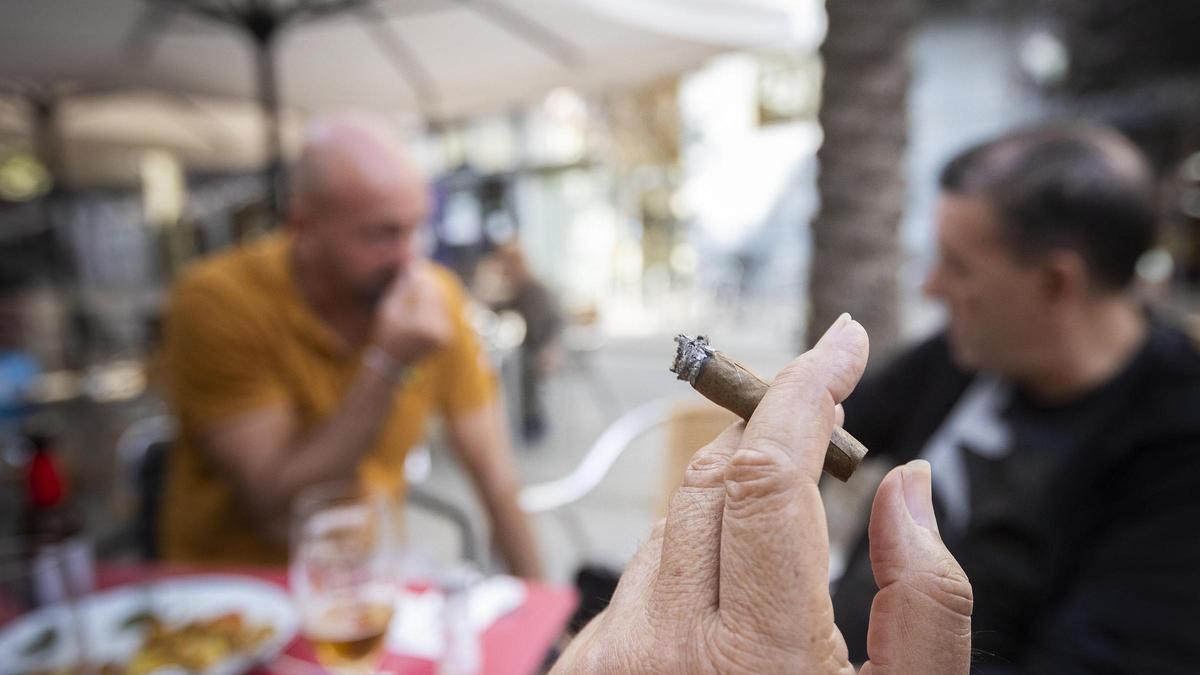 Fumadores con un cigarrillo en una terraza.