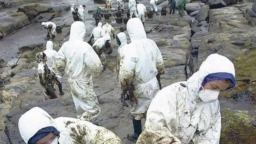 Un grupo de voluntarios retira chapapote de la costa de Muxía, en noviembre de 2002.  // Lavandeira JR.