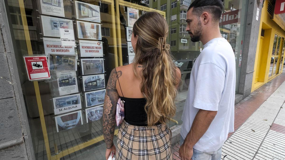 Dos jóvenes miran ofertas en una inmobiliaria.