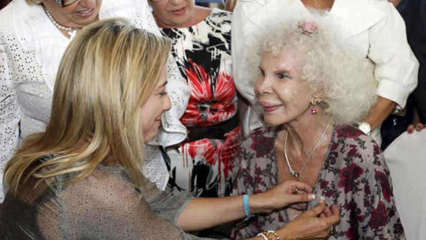 La alcaldesa de Alicante, Sonia Castedo (i), hace entrega a la Duquesa de Alba de la insignia de la ciudad en el transcurso del acto en el que también ha recibido la insignia de oro y brillantes de la peña taurina &quot;Tertulia amigos de Nimes&quot;