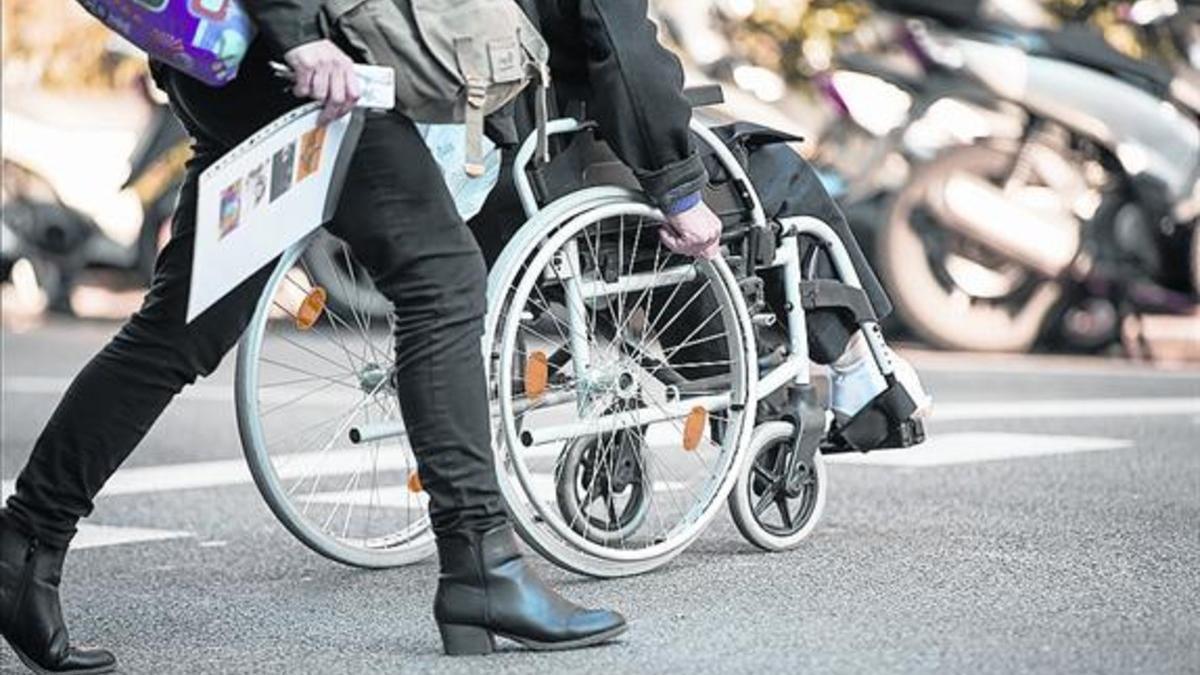 Un ciudadano cruza el paso de peatones en silla de ruedas.