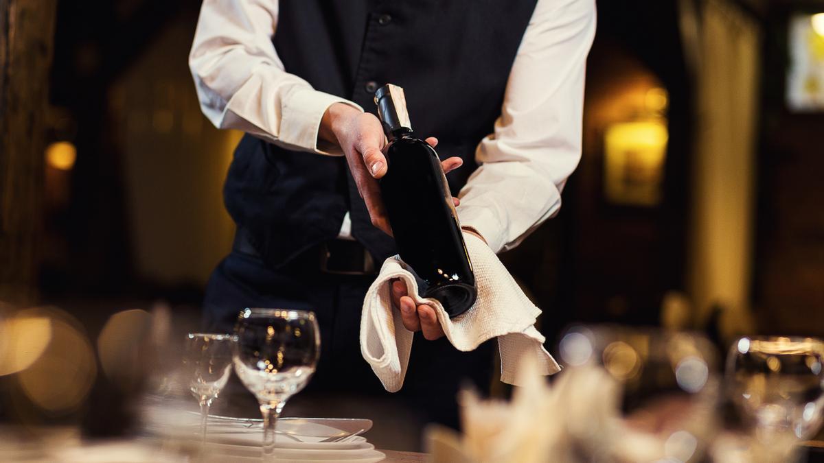 Un camarero muestra una botella de vino en un restaurante.