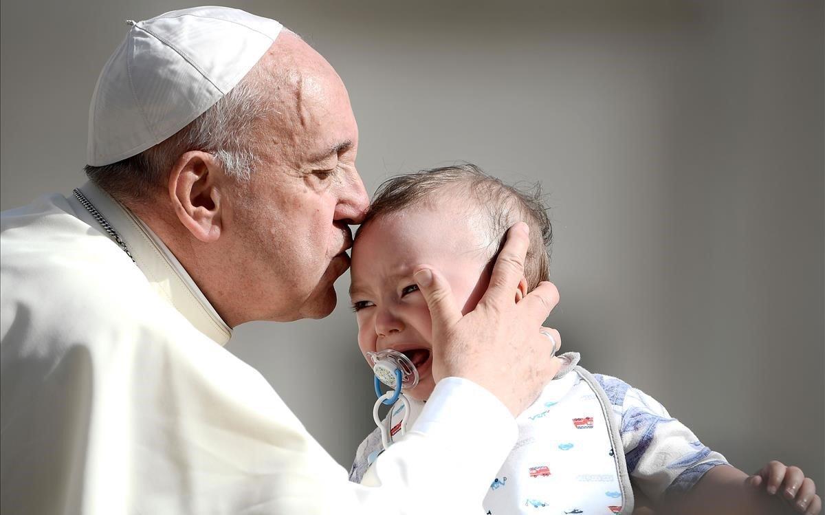 El Papa Francisco besa a un pequeño a su llegada a la audiencia general semanal en la plaza de San Pedro en el Vaticano