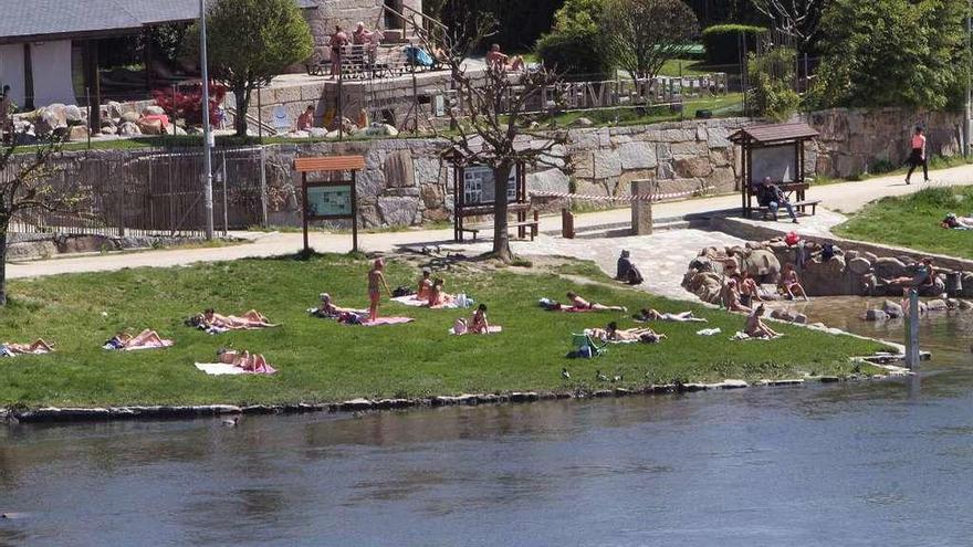 Bañistas tomando el sol en A Chavasqueira, todavía con las termas cubiertas. // Iñaki Osorio