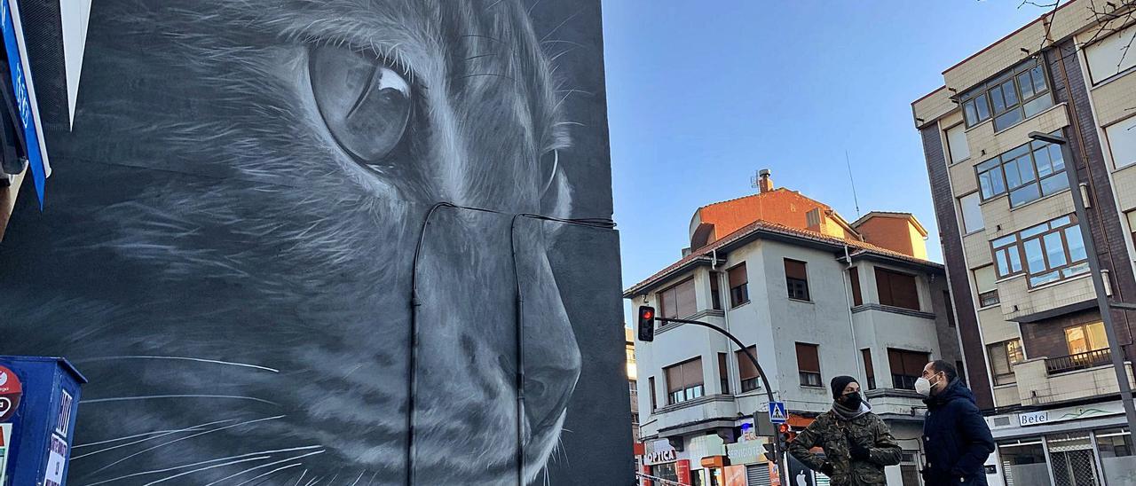 Ángel Caballero, alias “Xolaka”, a la izquierda, con el alcalde de Siero, ayer, ante el grafiti en la avenida de Oviedo de Lugones. | R. A. I.